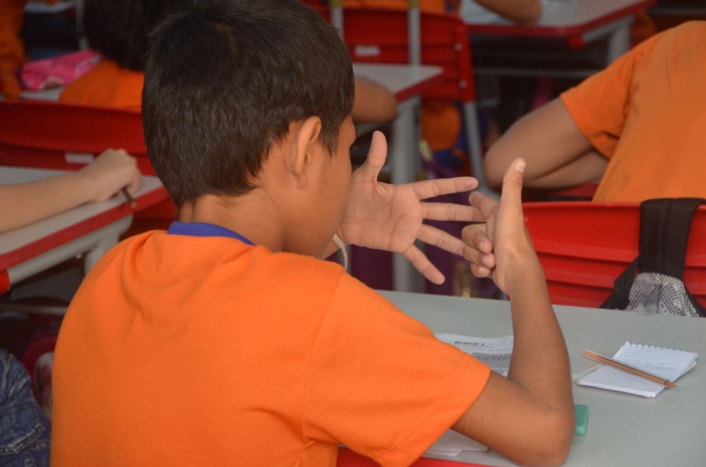 A young child in class counting using their fingers